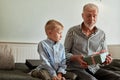 Generation. grandfather and grandson with gift box sitting on couch at home Royalty Free Stock Photo