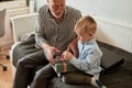 Generation. grandfather and grandson with gift box sitting on couch at home Royalty Free Stock Photo