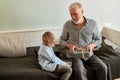 Generation. grandfather and grandson with gift box sitting on couch at home Royalty Free Stock Photo