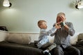 Generation. grandfather and grandson with gift box sitting on couch at home Royalty Free Stock Photo