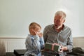 Generation. grandfather and grandson with gift box sitting on couch at home Royalty Free Stock Photo