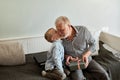 Generation. grandfather and grandson with gift box sitting on couch at home Royalty Free Stock Photo