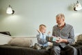 Generation. grandfather and grandson with gift box sitting on couch at home Royalty Free Stock Photo