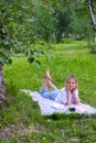 Teen girl lies listens to music in headphones on the grass in the park with books and notebooks Royalty Free Stock Photo