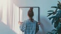 Generative AI Back view of woman hanging copy space picture frame on white wall in apartment. Female hold blank po Royalty Free Stock Photo