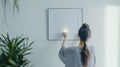 Generative AI Back view of woman hanging copy space picture frame on white wall in apartment. Female hold blank po Royalty Free Stock Photo