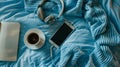 Generative AI Blue knitted sweater coffee with milk notebook headphones smart phone on bed top view Women clothing