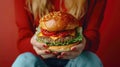 Close-up of hands holding a juicy cheeseburger.