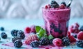 Fresh Berry Smoothie in a Tall Glass with a Striped Straw, Vibrant Purple Drink Accompanied by Blackberries on a Light Blue