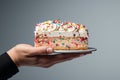 Generative AI Image of Hand Holding a Slice of Birthday Cake on Plain Background Royalty Free Stock Photo