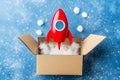 A generative AI image of a rocket lifting off from a cardboard box in a blue setting Royalty Free Stock Photo