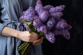 Generative AI International Women& x27;s Day. A woman in a blue dress holds a lush bouquet of lilacs. Close-up view