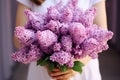 Generative AI International Women's Day. A woman in a pink dress holds a lush bouquet of lilacs. Close-up view