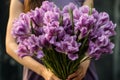 Generative AI International Women& x27;s Day. A young woman in dress holds a lush bouquet of purple irises. Close-up