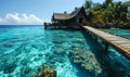 Serene tropical paradise with a wooden pier leading to overwater bungalows in a crystal-clear turquoise sea against a vibrant blue Royalty Free Stock Photo