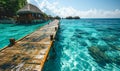 Serene tropical paradise with a wooden pier leading to overwater bungalows in a crystal-clear turquoise sea against a vibrant blue Royalty Free Stock Photo