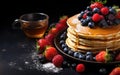 Stack of golden pancakes with fresh blueberries and strawberries on the side, accompanied by a bowl of maple syrup on a dark Royalty Free Stock Photo