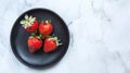 Generative AI Top view of black plate on white marble background Three strawberries flat lay Copy space business c Royalty Free Stock Photo