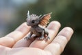 Generative AI, very small, tiny dragon in the hands, very cute and adorable.