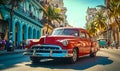 Vintage red classic car cruising on a sunny street in Havana with historical architecture and tropical vibes, capturing the Royalty Free Stock Photo