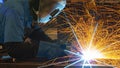 A worker welder in a helmet performs gas welding