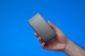 Generic black smartphone held by male hand. Close up studio shot, isolated on blue background Royalty Free Stock Photo