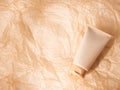 Generic cosmetic body skin care product in beige plastic tube on crumplead paper background