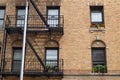 Generic Exterior of an Old New York City Apartment Building with Fire Escapes and Potted Plants in Windows Royalty Free Stock Photo