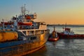 Generic of industrial harbor with big white blue ship, red boats docked. Seascape in sun light. Sky gradient Royalty Free Stock Photo