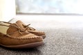 Generic mens suede moccasin slippers on carpet next to sofa in a