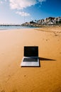 Generic notebook laptop on sunny deserted sandy beach background Royalty Free Stock Photo
