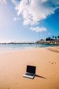 Generic notebook laptop on sunny deserted sandy beach background