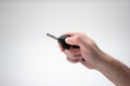 Generic plastic black car key fob held by Caucasian male hand. Close up studio shot, isolated on white background