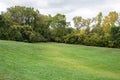 Empty Rolling Grassland Surrounded by Trees with Cloudy Sky