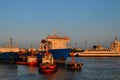 Generic view of industrial harbor with big white blue ships, red boats, vessels docked in harbor, warm orange sunset light Royalty Free Stock Photo