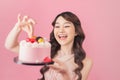 Generous woman holding birthday cake front pink background