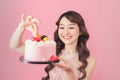 Generous woman holding birthday cake front pink background