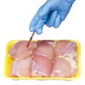 Genetic injection into raw chicken meat isolated. Genetically modified food and syringe in hand with blue glove