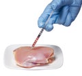 Genetic injection into raw chicken meat on square plate isolated on white background. Genetically modified food and syringe