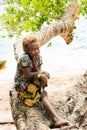 Solomon Island, shy girl with blond hair and dark skin sitting on tree trunk, South Pacific Ocean.