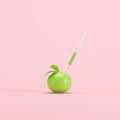 Genetically modified green apple with syringe on light pink background