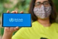 Geneva, Switzerland,2020. Girl wearing mask showing on her mobile phone screen, World health organization WHO landing page & Royalty Free Stock Photo