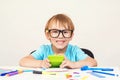 Genius boy in glasses is sitting at desk. Happy boy doing homework at home. Cute clever boy in glasses studying. Back to school. C
