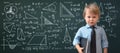 A genius kid, a child prodigy, a boy in a shirt with a tie on the background of a blackboard covered with formulas, back to school Royalty Free Stock Photo