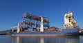 A long container ship with big cranes moored in the port of Genoa, Italy