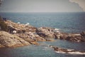 Genoa, Italy - the tourist village of Nervi, marine baths. Beach umbrella and a deck chair on a rocky coastline.