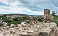 Genoese fortress in the Crimea on the background of houses. A ruined ancient tower made of stones and blocks in the city.