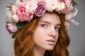 Gentle beautiful girl with red hair in wreath of roses