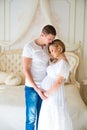 Gentle beautiful pregnant couple near tulle curtains