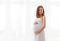 Gentle elegant pregnant woman in a white dress